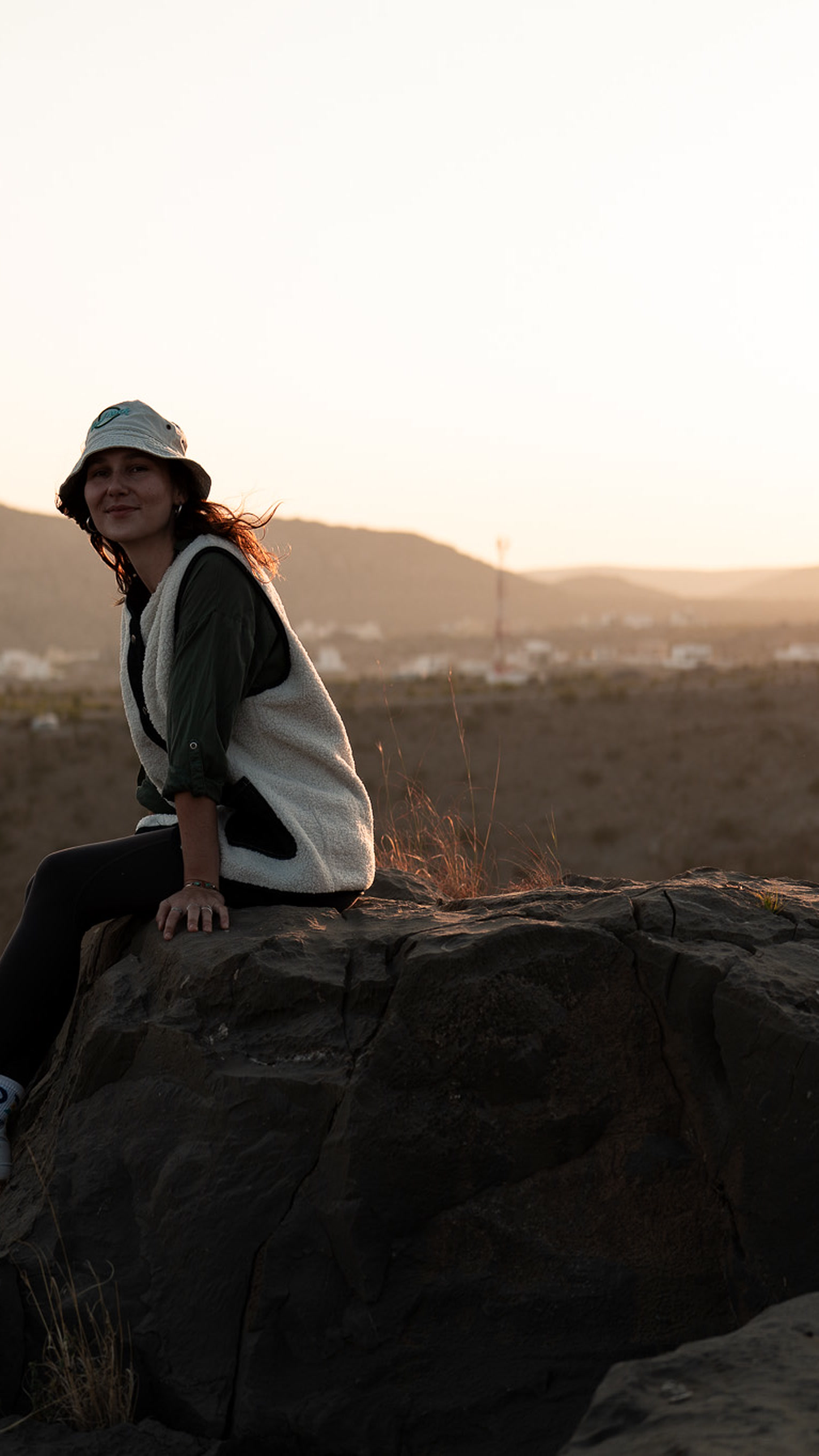 Victoria sitting on a rock at sunset